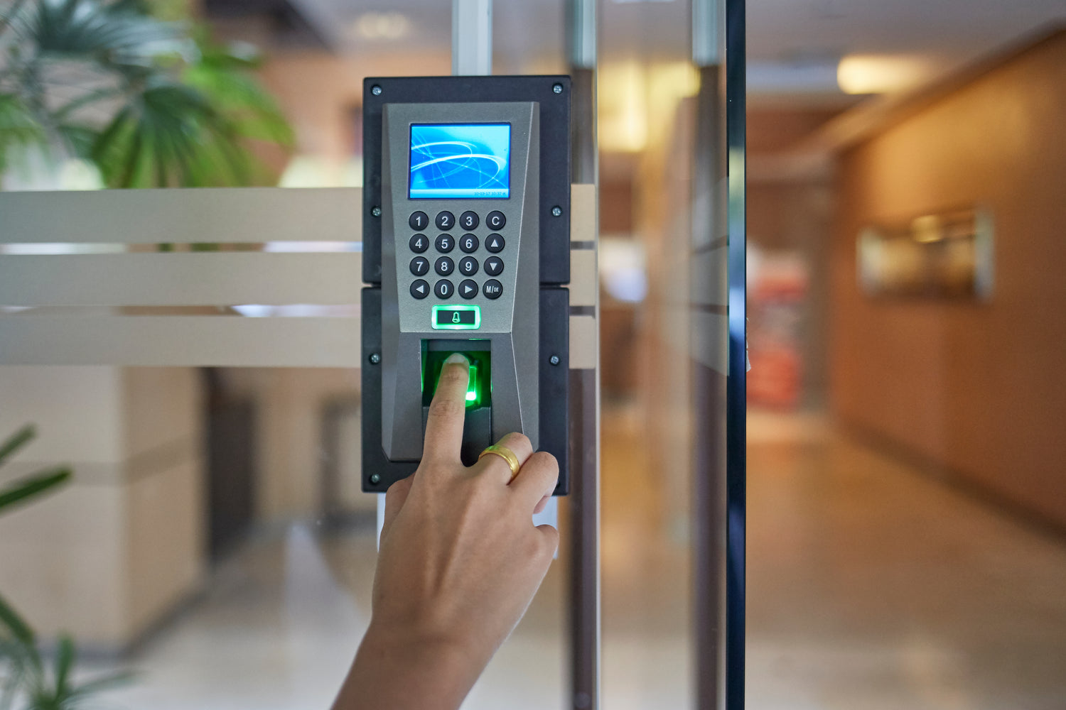 A hand holding a finger to a biometric access panel
