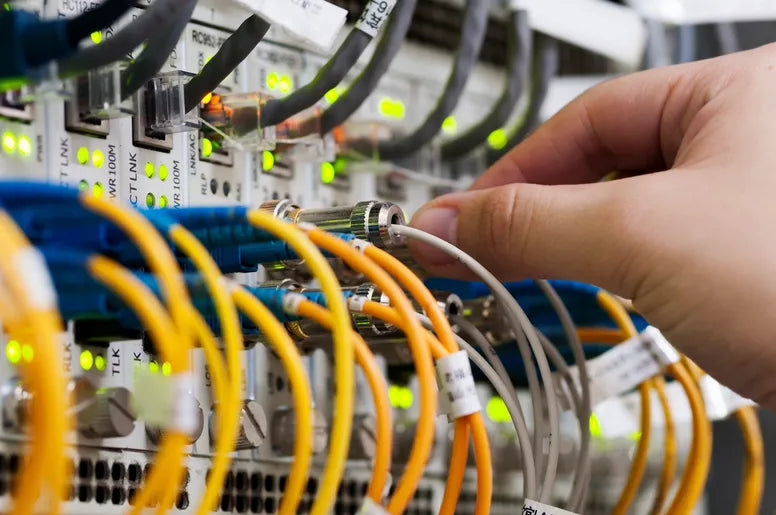 A hand plugging wires into a panel full of wires