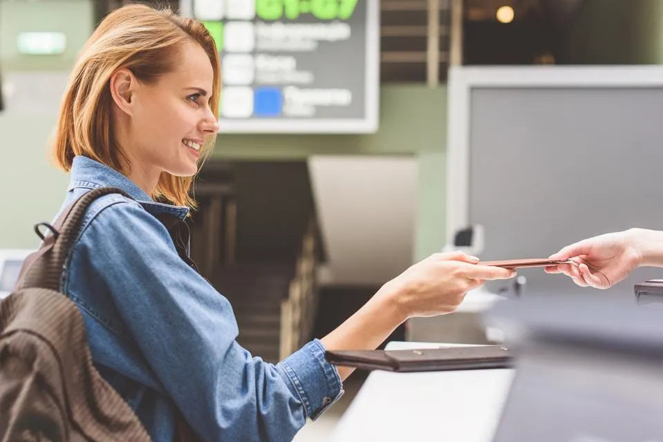 A woman with a backpack receiving an ID card from someone else