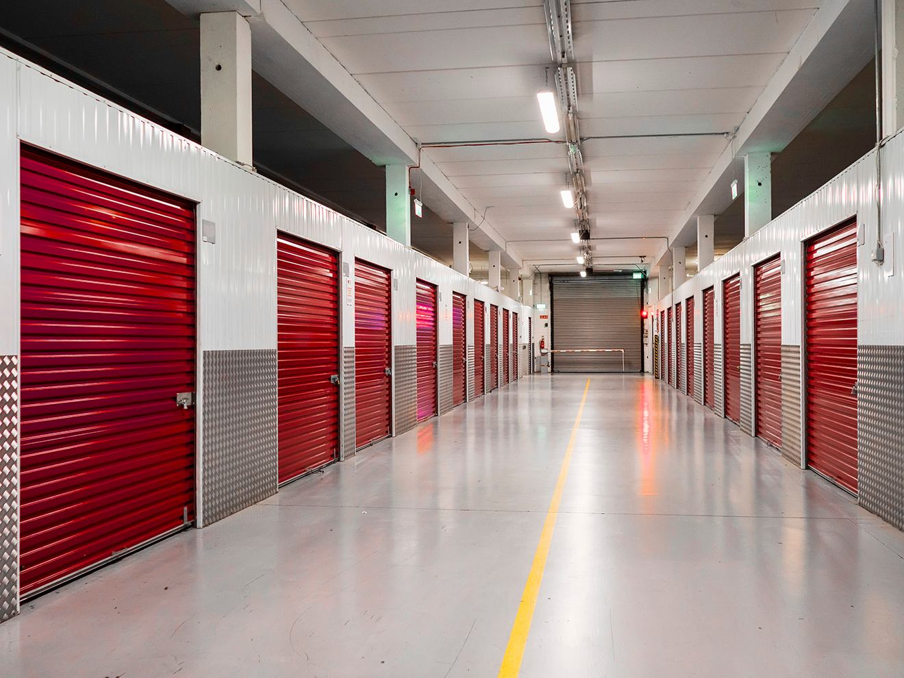 A hallway with red self-storage doors lining both walls