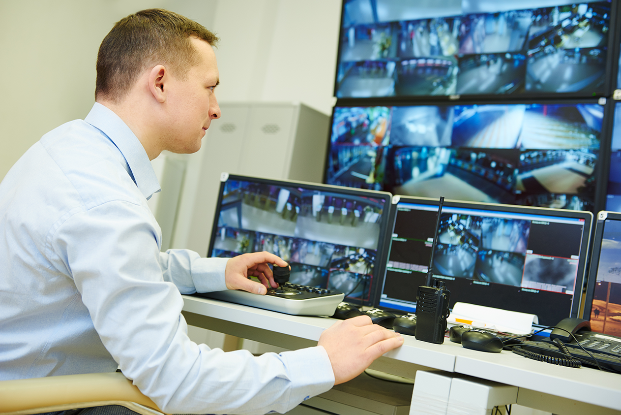 A man in front of computer screens showing facility camera footage
