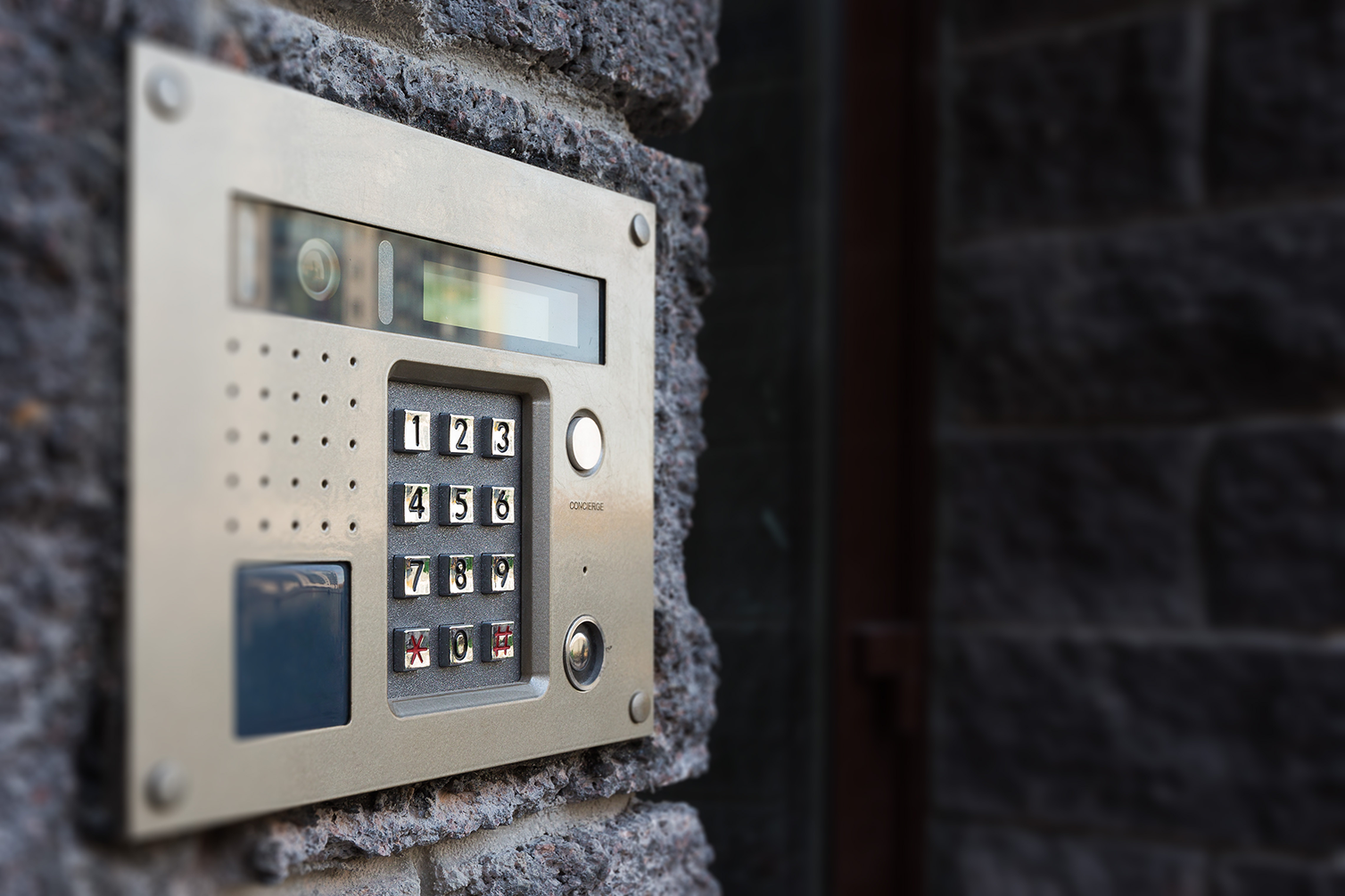 An intercom system panel embedded in a brick wall