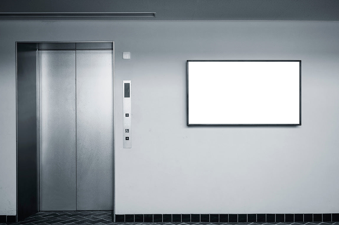 A blank TV mounted on a wall, next to a closed elevator door