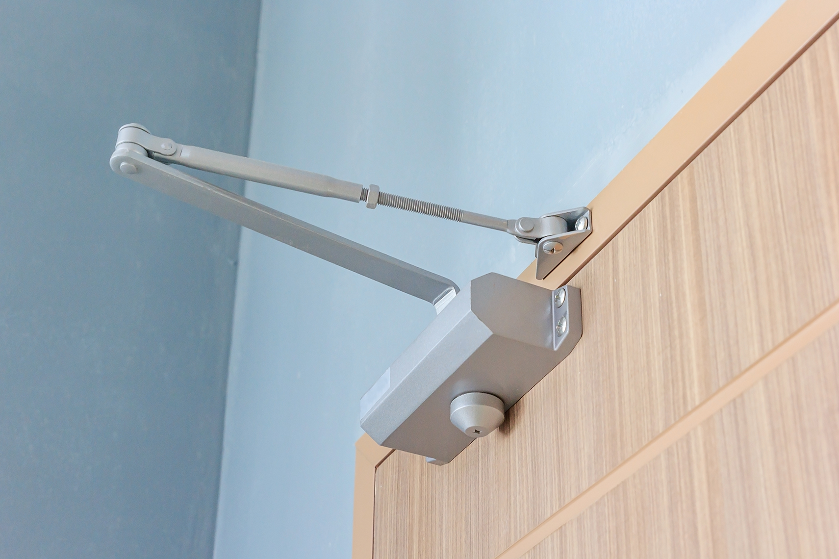 A door closer at the top of a wooden door