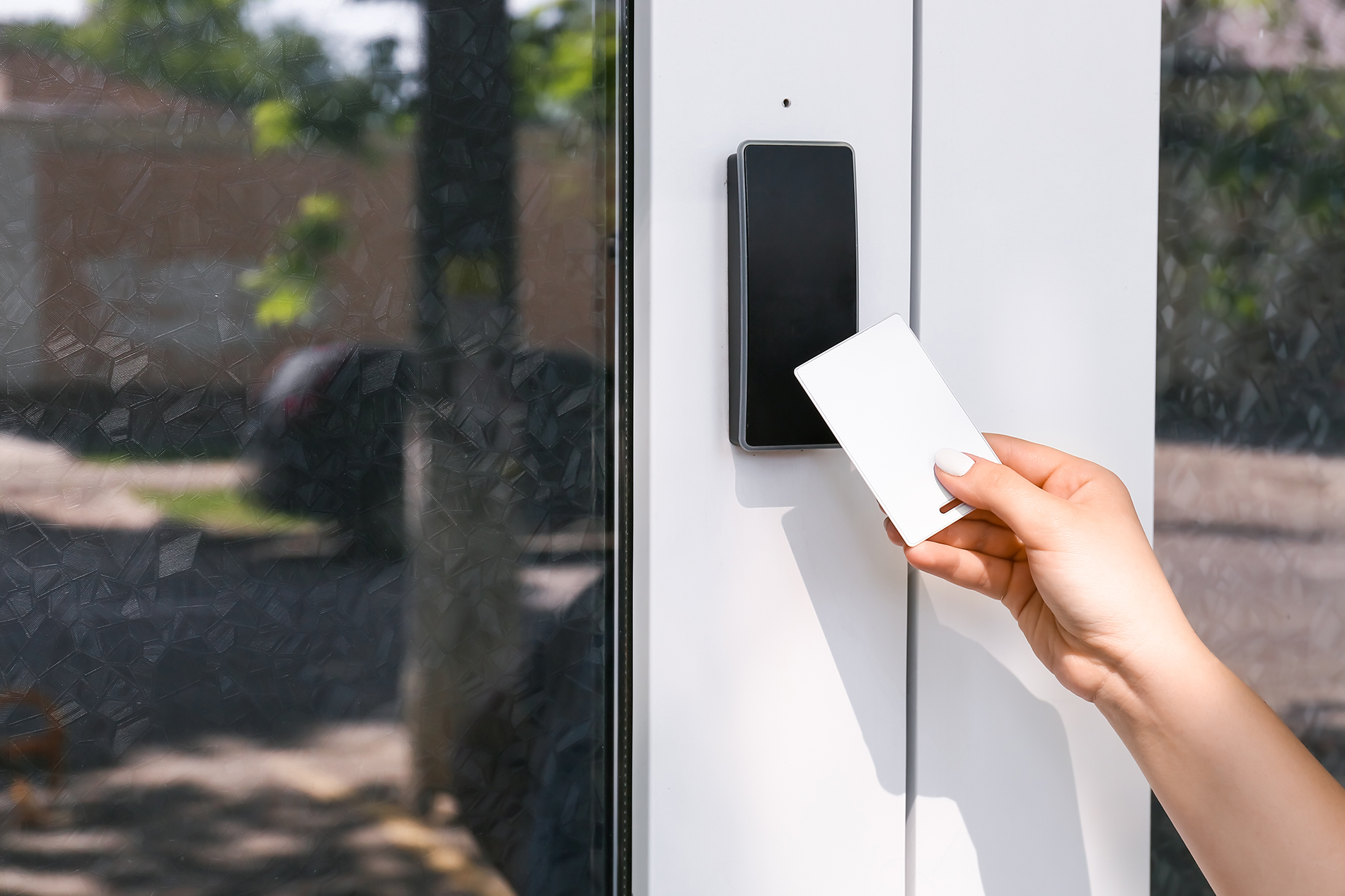 A hand holding a blank card in front of an electronic card reader
