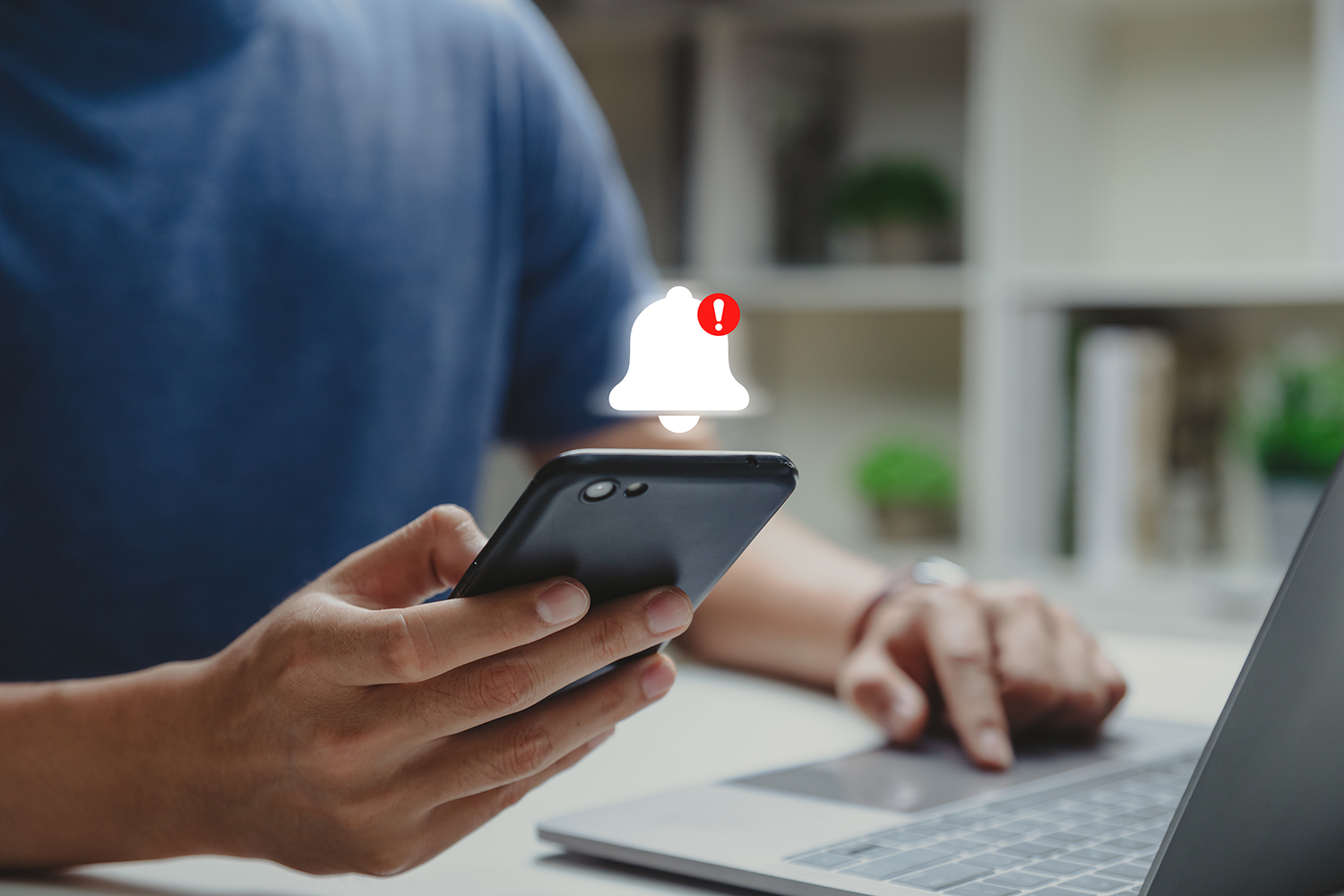 A hand holding a smartphone, with an alarm icon floating above it